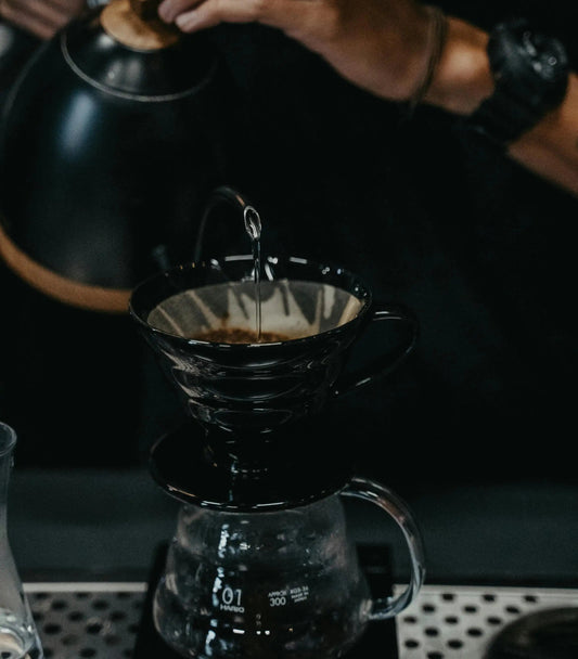 barista che versa acqua in the coffee